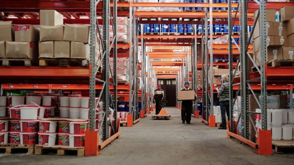 Interior de un almacén de guardamuebles con estanterías y operarios trasladando bultos